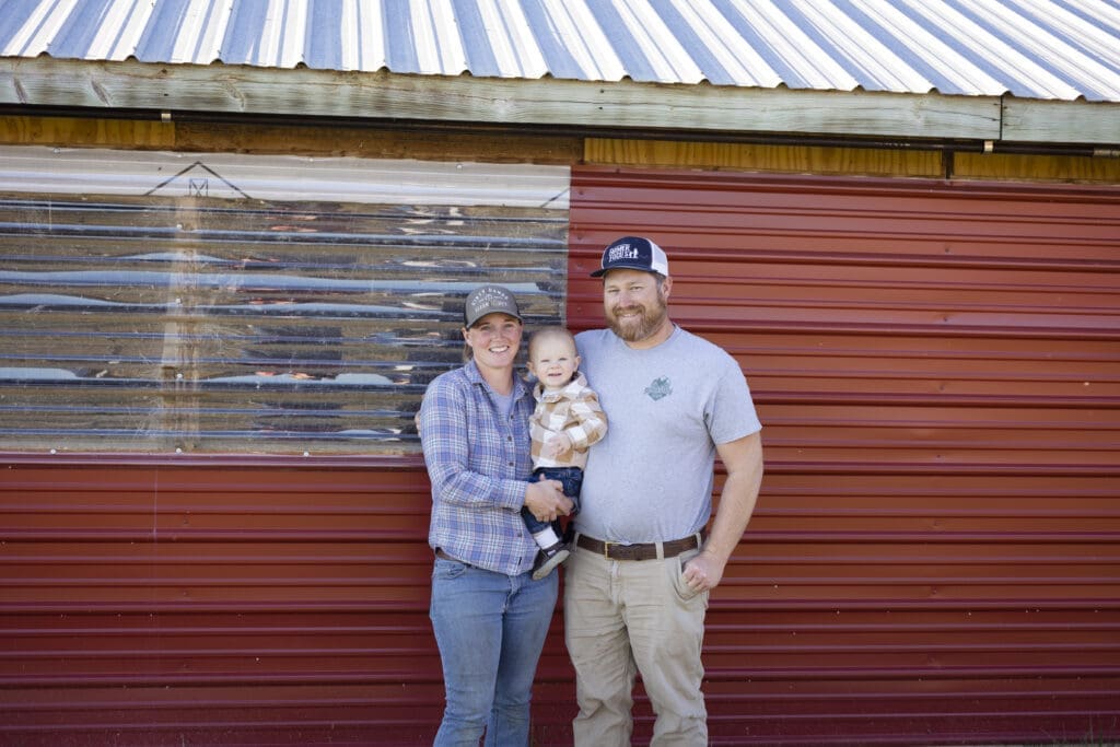 Farmers standing next to the chicken house with window for natural light