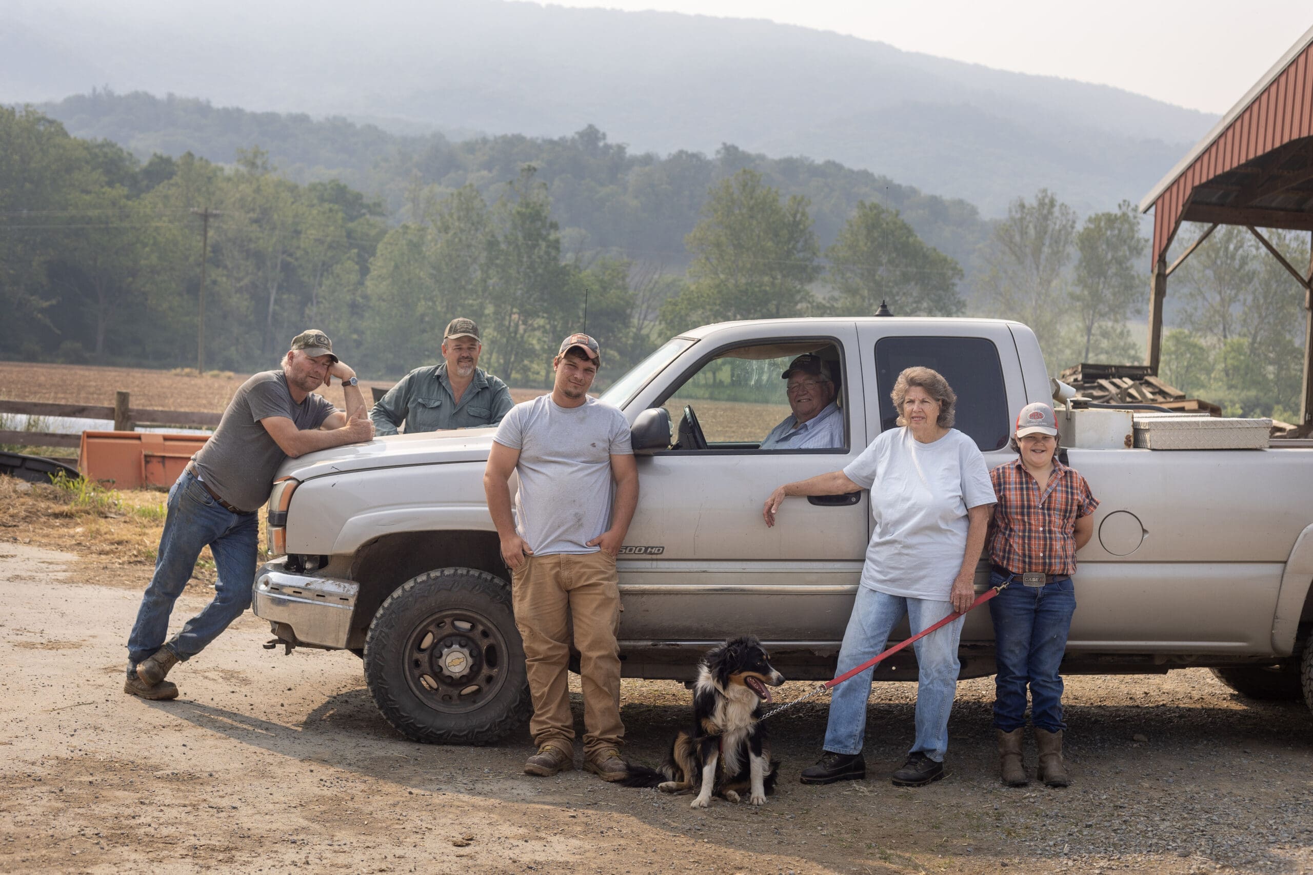 Farmer Focus Farm family standing by the truck with their dog.